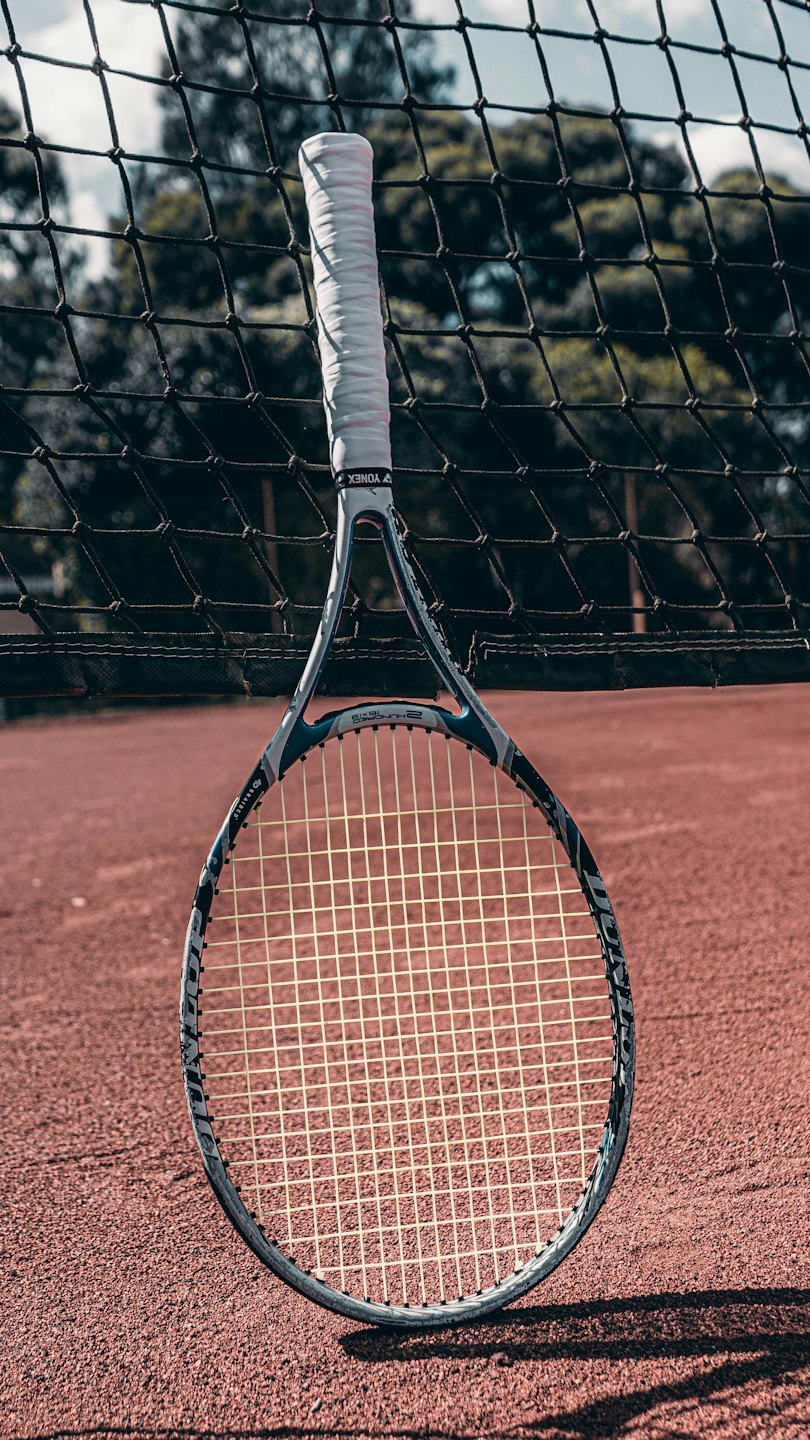 Una raqueta de tenis descansa contra la red de la cancha de tenis.